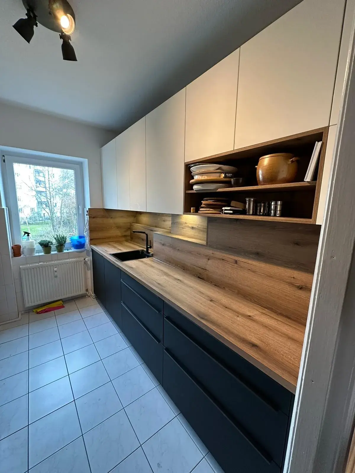 Küche Rostocker KTV 1 Unterschrankzeile in schwarz mit Holzoptik Arbeitsplatte und Rückwand und weißen Hängeschränken mit Regal