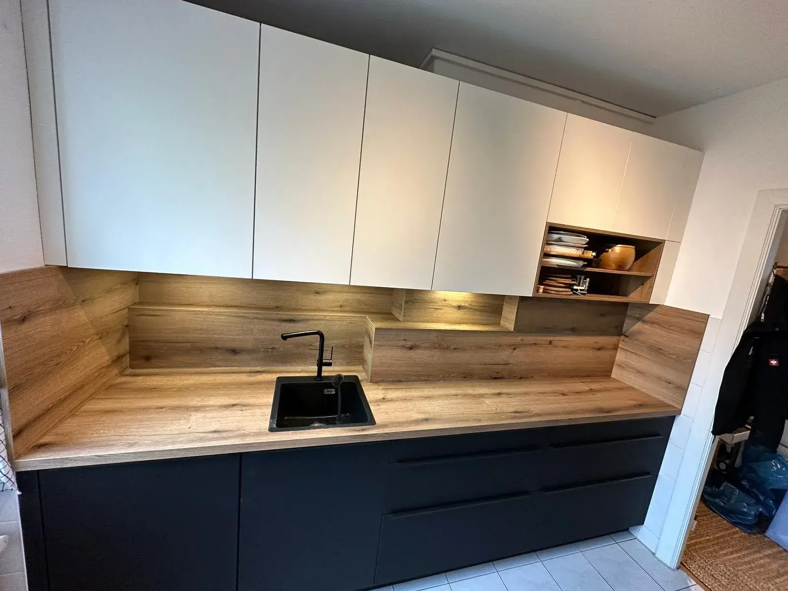 Küche Rostocker KTV 6 schwarze Küchenzeile mit Holzarbeitsplatte und Rückwand und weißen Hängeschränken